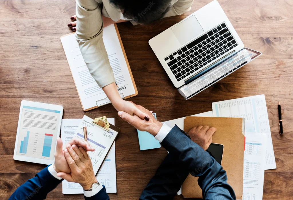 A group of people sitting around a table with papers.