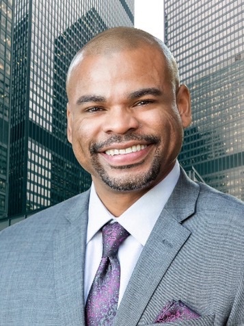 A man in a suit and tie smiling for the camera.